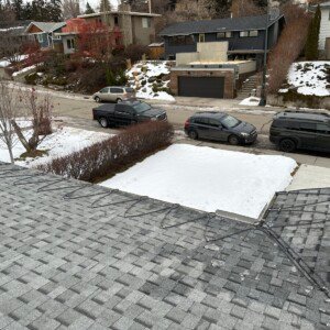 Overhead view of a residential shingle roof serpentine heat cable system overlooking a Calgary street layout.