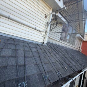 Heavy-duty roof de-icing cables installed along a steep roof pitch near home siding to protect structure from water damage.