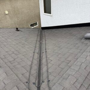 De-icing cable routed along roof valley flashing and a stucco wall junction to protect against ice damming.