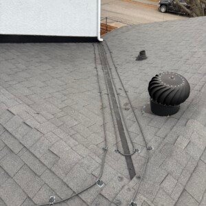 Close-up of a double roof valley heat cable layout next to a whirlybird turbine vent on a Calgary residence.